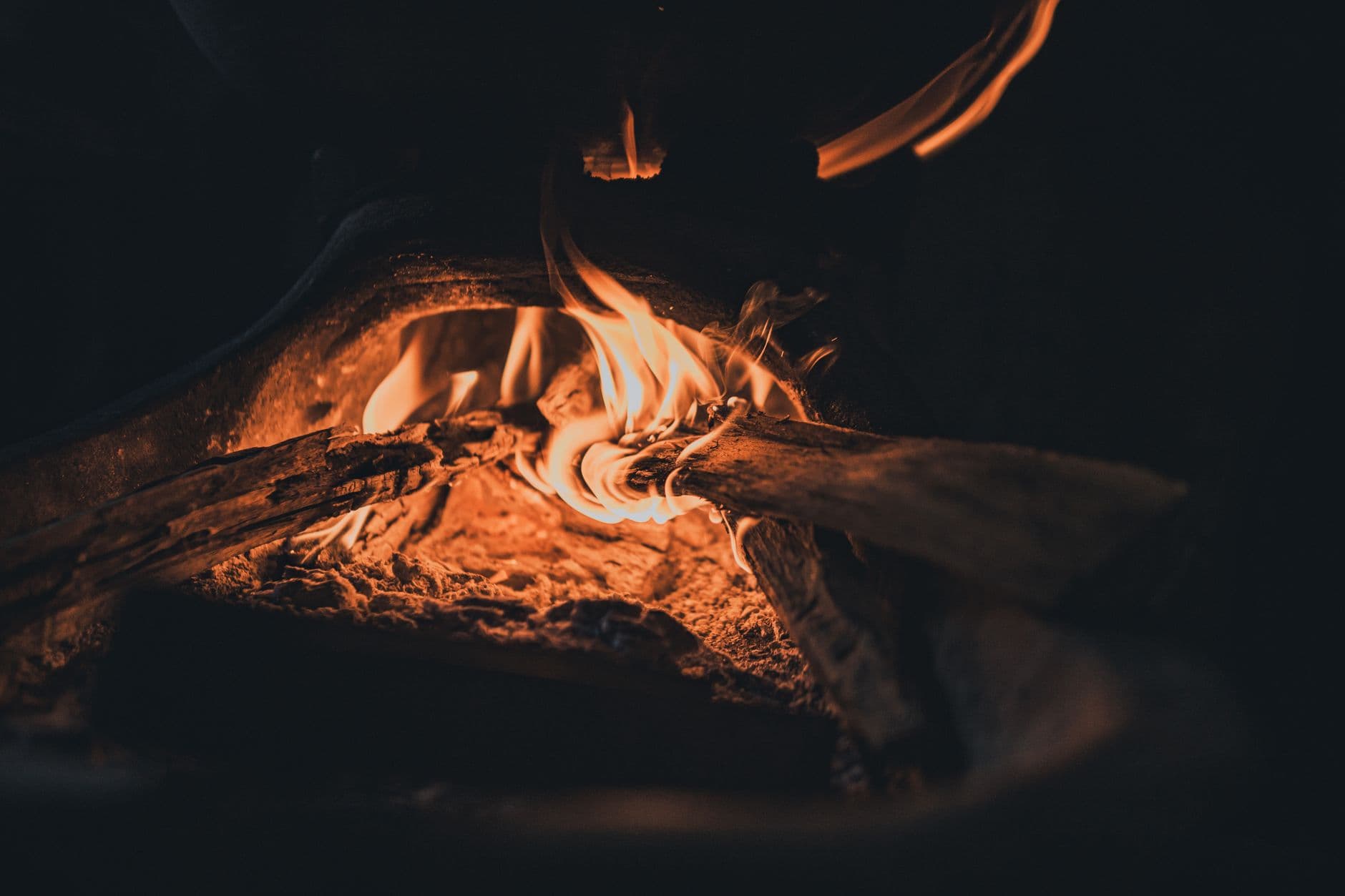 Close-up of a wood fire in a stove emitting warm, rustic flames during nighttime.